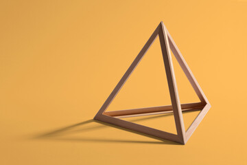 Wooden triangular frame on yellow background