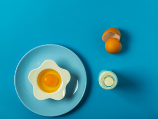 egg yolk and white in a bowl and plate on a solid color background background