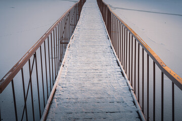Bridge with metal banisters over the frozen lake