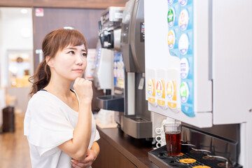 Fototapeta na wymiar ドリンクバーで飲み物を選ぶ女性 