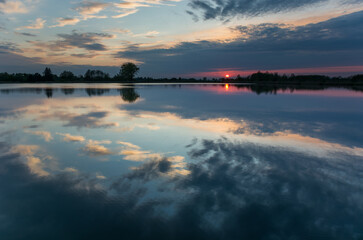 Colorful clouds reflected in the calm lake at sunset