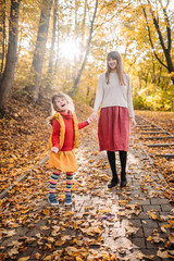 mom with emotional and hyperactive daughter are walking in the park