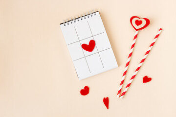 Notebook with red hearts above pastel background.