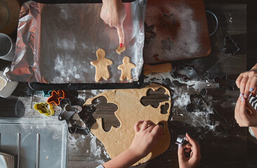 Making gingerbread man, ginger cookie dough. The concept of a feast in the house, a family dinner. New Year traditions concept and cooking process. Cookies on dark brown wooden table. 
