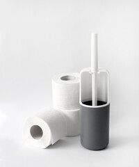 White and gray plastic toilet brush and toilet paper on white background