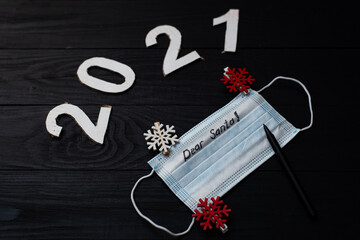New Year's letter to Santa on the mask. Figures 2021 and a medical mask on a black background