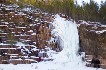 Rock climber climbs the winter frozen waterfall