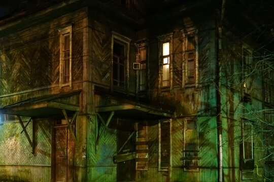 Abandoned creepy wooden house with a glowing window. Horror
