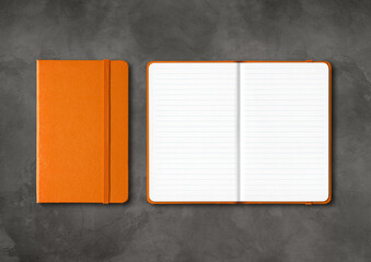 Orange closed and open lined notebooks on dark concrete background