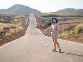 A woman wearing a hat and glasses is standing in the middle of the road.