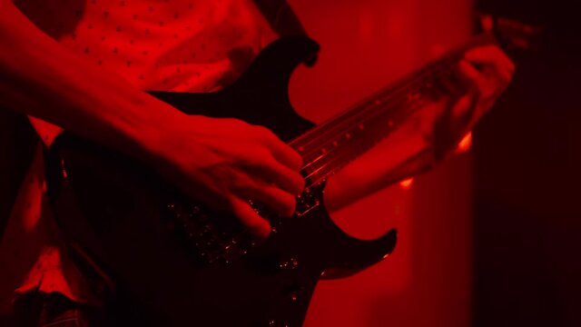 The male composer plays a six-string electric guitar and loudly. Performing an energetic rock song. Close-up of playing an electric guitar