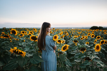 happy woman stands in a field of sunflowers and smiles. Sense of freedom, rights and freedom of...