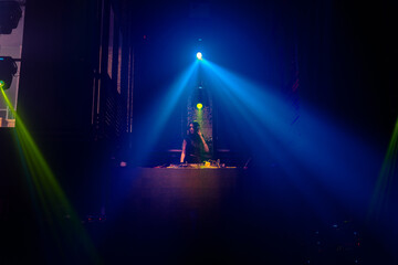 DJ on stage in disco night club mixing techno music beat . Nightlife and dance party .