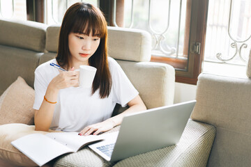 Young adult asian woman work and study at home on virus pandemic social issuse.