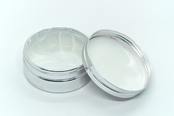 White cream in open round aluminum metal tin on white background. Natural cosmetic product. Face and body skin care, cosmetic products.