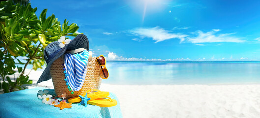 Concept of summer beach holiday on tropical island Maldives. Beach bag, blue hat with frangipani...