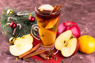 Christmas mulled wine with apples and citrus fruits and spices in a tall glass.