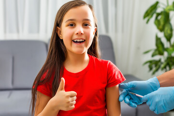 Little girl in the doctor's office is vaccinated. Syringe with vaccine against covid-19...