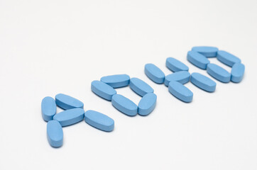 Close- up of ADHD  word written  with  blue pills on white background .