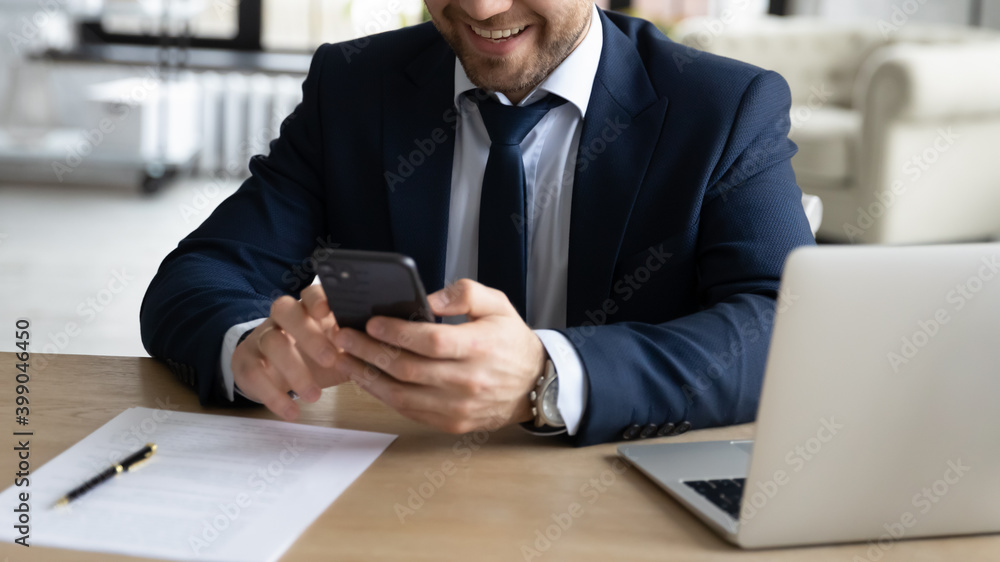 Poster Close up successful smiling businessman using smartphone, sitting at work desk in office, happy employee looking at phone screen, reading message, email, browsing apps, chatting online during break