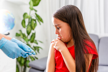 A doctor injects a vaccine to a little girl. The girl is afraid and crying.