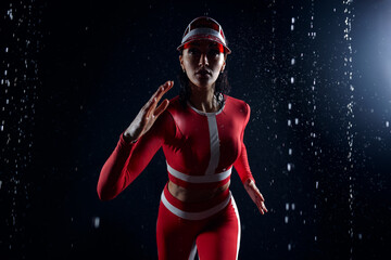 Beautiful young girl in sportswear runing in aqua studio. Drops of water spread about her fitness body. The perfect figure on the background of water splashes. Bad weather for sport