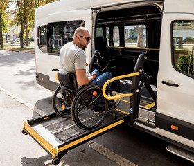 A man in a wheelchair on a lift of a vehicle for people with disabilities