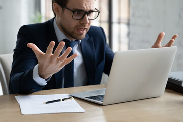 Close up annoyed unhappy businessman wearing glasses looking at laptop screen, having problem with...