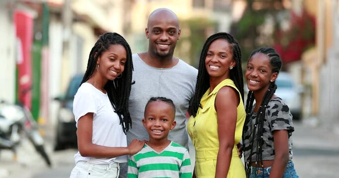 Happy African family portrait standing for photo outside. Cheerful black parents and children