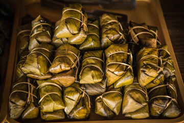 Steamed glutinous rice is made from rice with banana inside, wrapped in banana leaves, tied with bamboo sticks, called Khao Tom Mud.