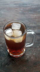 A glass of iced tea on a wooden table. Focus selected, background blur