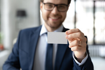 Close up confident businessman showing empty business card at camera, smiling executive manager...
