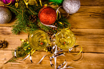 Two wineglasses with champagne and different christmas decorations on wooden table. Top view