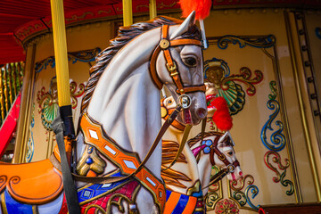 Old French carousel in a holiday park. Three horses and airplane on a traditional fairground vintage carousel. Merry-go-round with horses.