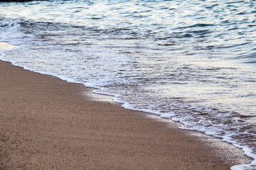 The beach with sea waves running on the sand. Beautiful view on the waves