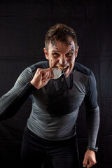 Handsome man in sportswear is insanely rejoicing at the received silver medal in the studio on a black background