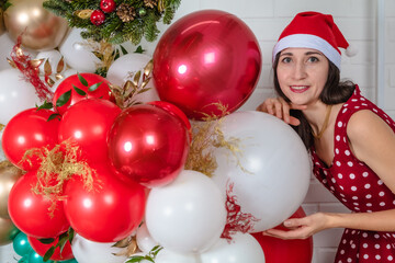 woman in a christmas hat, in a festive location with
  inflatable balloons.Concept congratulation merry christmas, happy new year