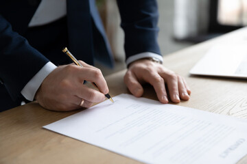 Close up businessman signing contract, making successful purchasing or investment deal, filling legal document, candidate employee signing job agreement after interview, standing at office desk
