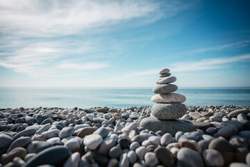 A column of gray stones on the seashore against the background of a blue clear sky
