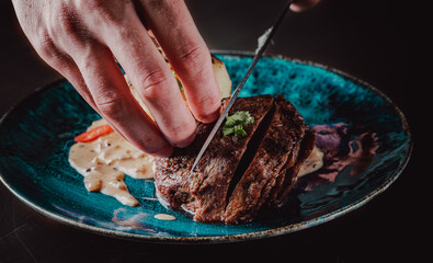 chef hand cut Grilled beef steak filet mignon in plate on wooden table