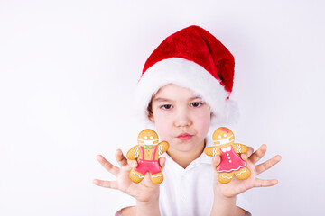 a boy in a Santa Claus hat holds Christmas gingerbread on a white background
