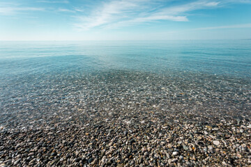 Transparent water on the seashore through which the shiny sea stones are visible