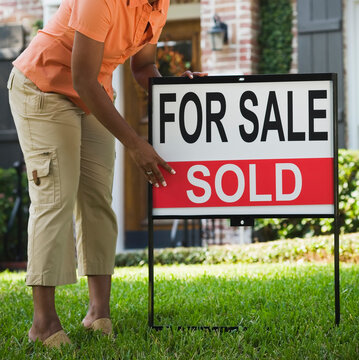 African woman next to Sold sign