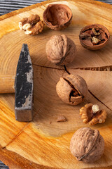 Small hammer and walnuts on a black wooden table. Top view. Close-up.