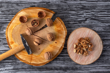 Small hammer and walnuts on a black wooden table. Top view.