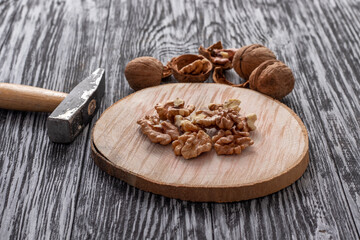 Small hammer and walnuts on a black wooden table.
