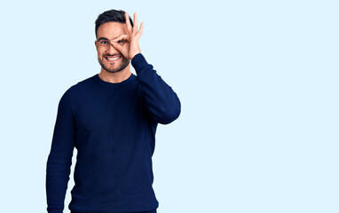 Naklejka premium Young handsome man wearing casual clothes doing ok gesture with hand smiling, eye looking through fingers with happy face.