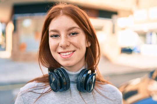 Young irish teenager girl smiling happy using headphones at the city.