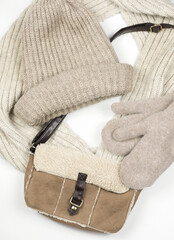 set of fashionable women's winter accessories on a white background top view. Autumn or winter hat and mittens. leather bag and scarf in beige neutral tones