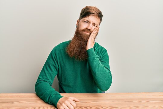 Young irish redhead man wearing casual clothes sitting on the table thinking looking tired and bored with depression problems with crossed arms.